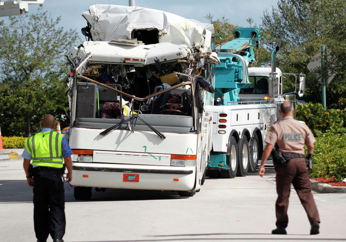 Law enforcement officers watch as a bus which hit a concrete overpass at Miami International Airport is hauled away, Saturday, Dec. 1, 2012 in Miami. The vehicle was too tall for the 8-foot-6-inch entrance to the arrivals area, and buses are supposed to go through the departures area which has a higher ceiling, according to an airport spokesperson. (AP Photo/Wilfredo Lee) (AP Photo/Wilfredo Lee)