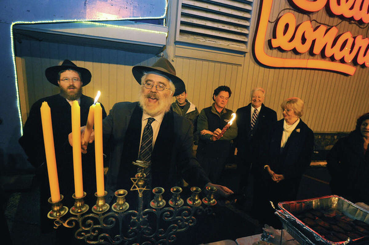 Hour photo/ Matthew Vinci Rabbi Yehoshua Hecht of Beth Israel Synagogue of Westport/Norwalk lights the menorah Monday at the annual celebration held at Stew Leonard's.