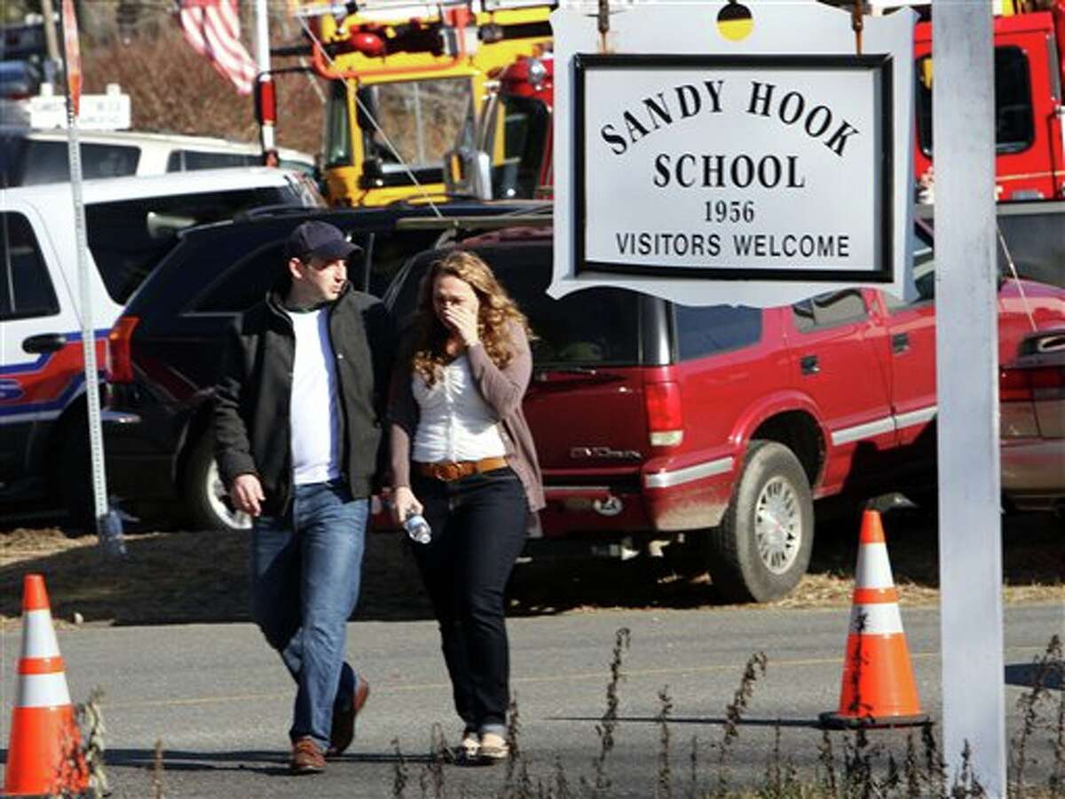 Parents walk away from the Sandy Hook Elementary School with their children following a shooting at the school, Friday, Dec. 14, 2012 in Newtown, Conn. A man opened fire inside the Connecticut elementary school where his mother worked Friday, killing 26 people, including 20 children, and forcing students to cower in classrooms and then flee with the help of teachers and police. (AP Photo/The Journal News, Frank Becerra Jr.) MANDATORY CREDIT, NYC OUT, NO SALES, TV OUT, NEWSDAY OUT; MAGS OUT