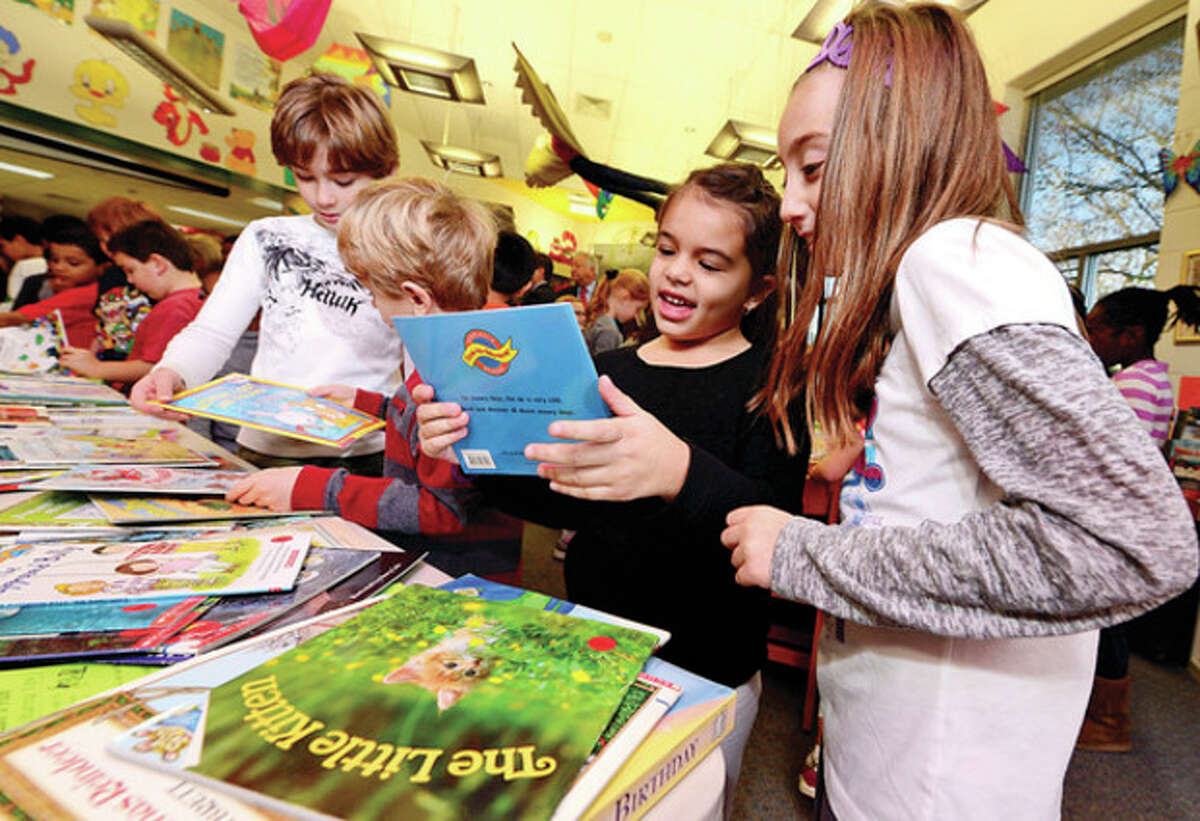 3rd grade Book Buddy, Sadi Sharkey, right, finds a book for kindergartner Mi DeMeglio during a free book distribution at Fox Run School Thursday. The a collaboration between United Way and Norwalk Read distributed nearly 2000 books Thursday morning and plans to give way over 12,000 this year. Hour photo / Erik Trautmann