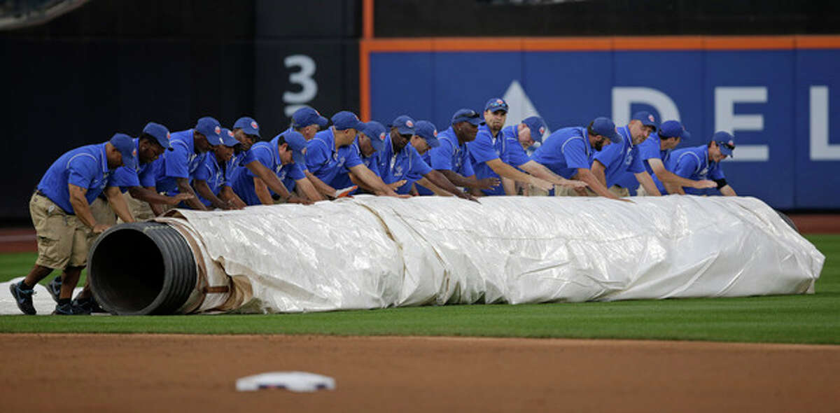 Groundskeepers roll the tarp onto the outfield as rain headed into the area after the first inning of a baseball game between the Washington Nationals and the New York Mets Thursday, Sept. 12, 2013, in New York. (AP Photo/Kathy Willens)