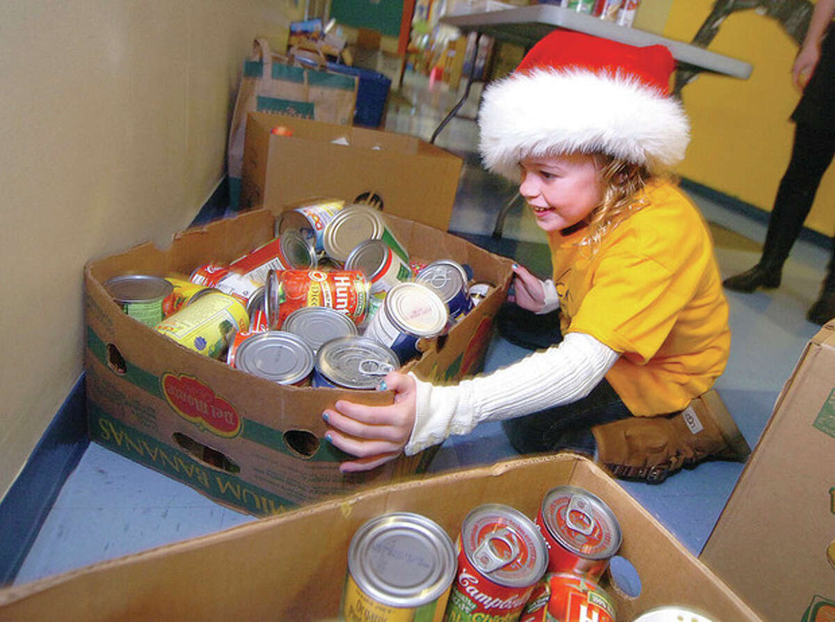 Hour Photo/Alex von Kleydorff. Aubrey Bransher moves some boxes of canned goods that students use for payment to buy stamps at The Columbus Magnet School Post Office