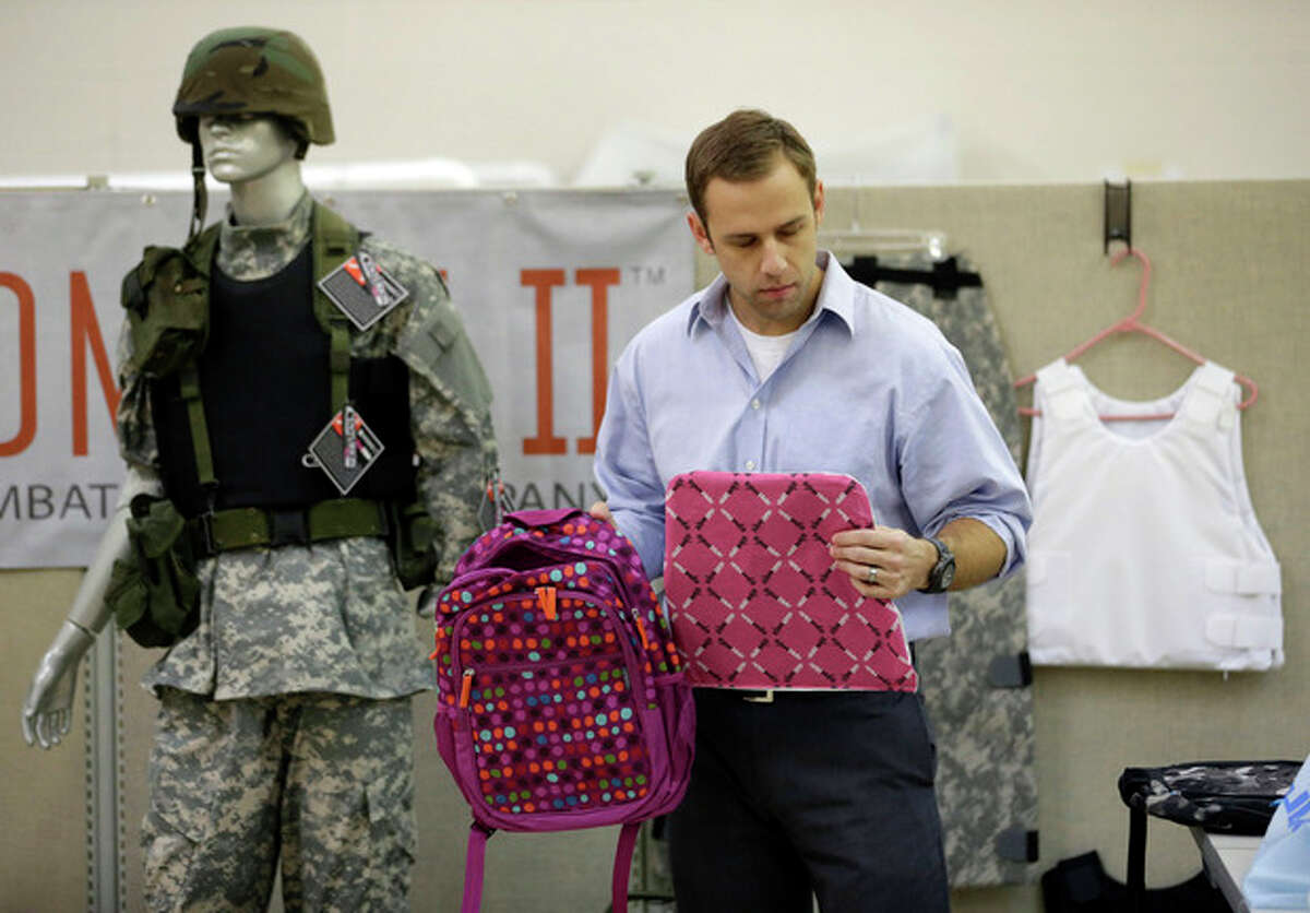 Rick Brand, Chief Operating Officer of Amendment II, holds a children's backpack, left, and anti-ballistic insert at the company's manufacturing facility in Salt Lake City, Wednesday, Dec. 19, 2012. Anxious parents reeling in the wake the Connecticut school shooting are fueling sales of armored backpacks for children emblazoned with Disney and Avengers logos, as firearms enthusiasts stock up on assault rifles nationwide amid fears of imminent gun control measures. At Amendment II, sales of children?’s backpacks and armored inserts are up 300 percent. (AP Photo/Rick Bowmer)