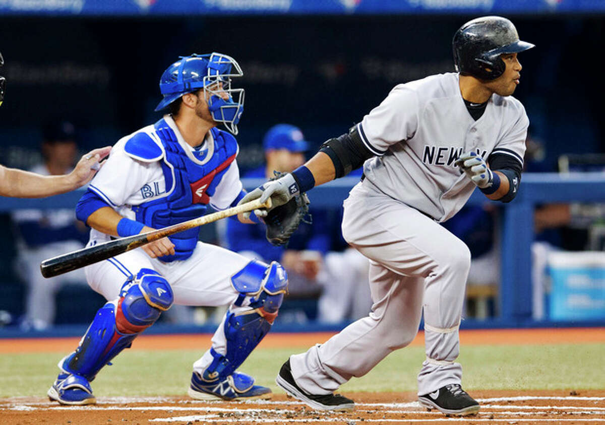 New York Yankees' Robinson Cano follows through on a base hit in front of Toronto Blue Jays catcher J.P. Arencibia, right, during the first inning of MLB American League baseball action in Toronto Wednesday, Sept. 18, 2013. (AP Photo/The Canadian Press, Mark Blinch)