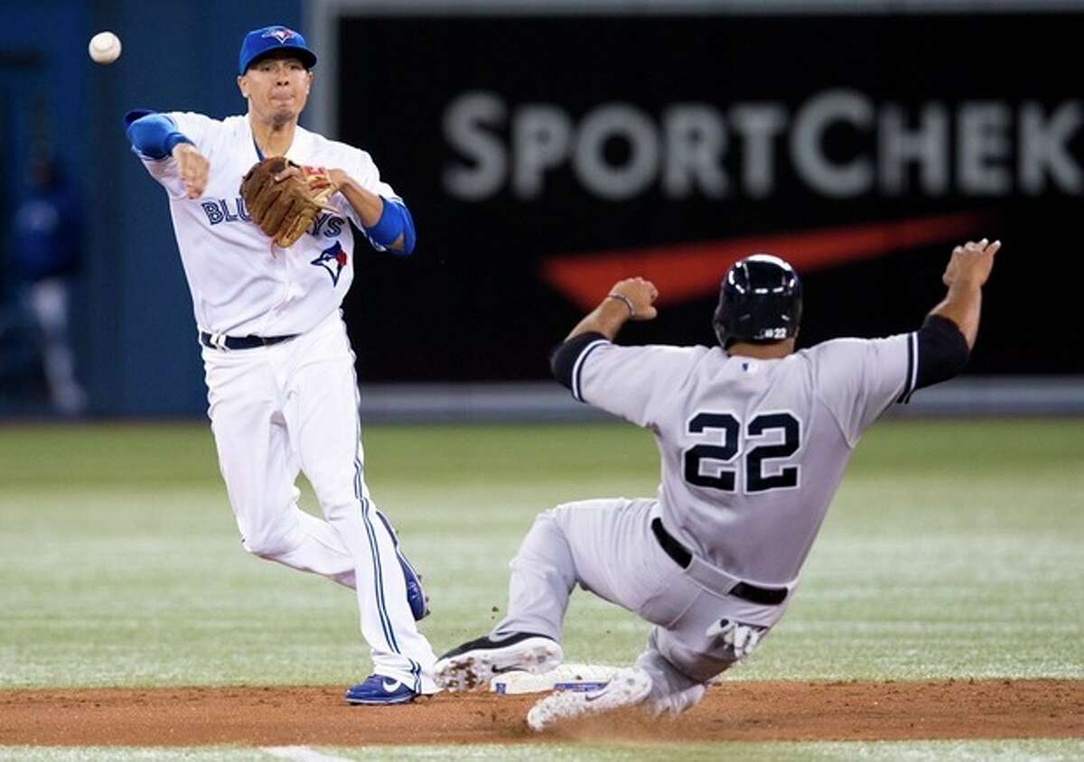 Toronto Blue Jays' Ryan Goins turns a double play over New York Yankees' Vernon Wells, right, during the fourth inning of MLB American League baseball action in Toronto Wednesday, Sept. 18, 2013. (AP Photo/The Canadian Press, Mark Blinch)