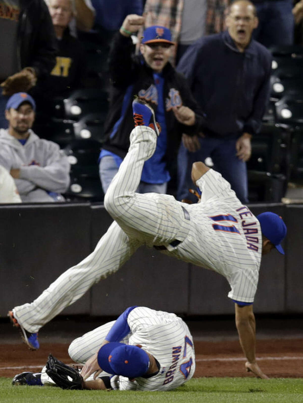 New York Mets shortstop Ruben Tejada (11) trips over left fielder Andrew Brown after catching San Francisco Giants' Angel Pagan's ninth-inning fly-out in left field during a baseball game on Wednesday, Sept. 18, 2013, in New York. (AP Photo/Kathy Willens)