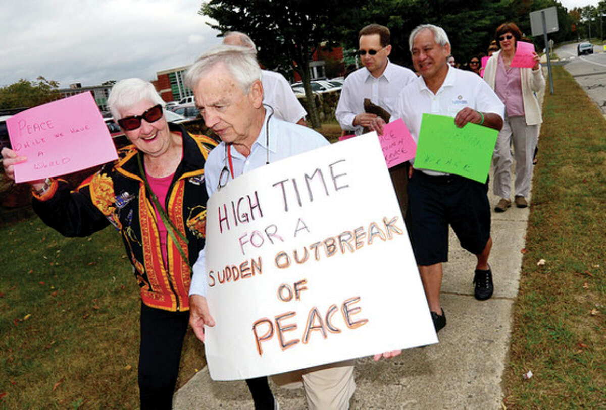 Hour photos / Erik Trautmann Above, Scott Kimmich and Mabel Dudeny participate in an outdoor Peace March from the front of the East Campus at Norwalk Community College building to the Post Road and back Saturday. Above right, Alex LaBonte holds a sign pledging to be nice.