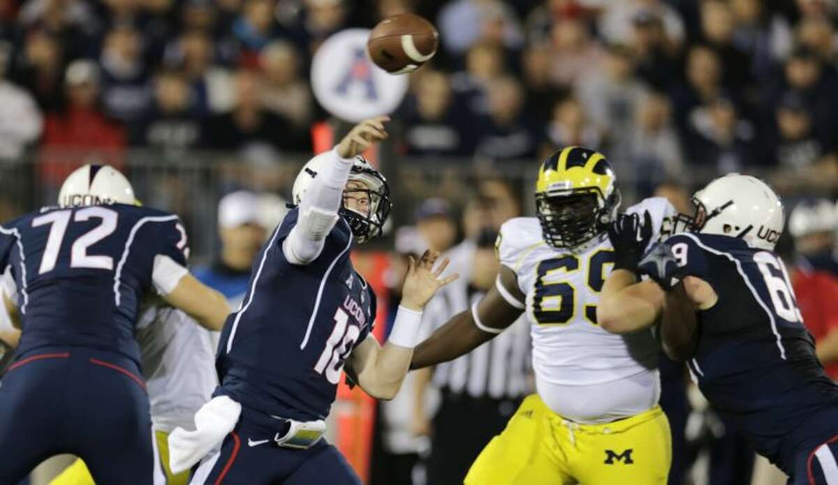 Connecticut quarterback Chandler Whitmer (10) throws as he is pressured by Michigan defensive tackle Willie Henry (69) during the first quarter of an NCAA college football game on Saturday, Sept. 21, 2013, in East Hartford, Conn. (AP Photo/Charles Krupa)