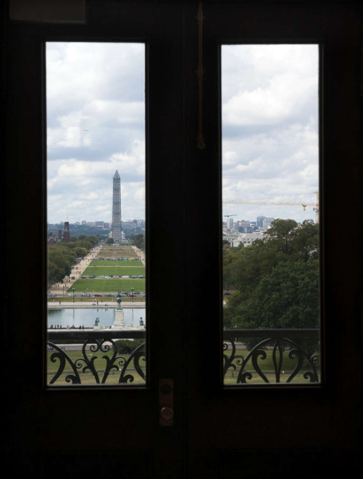 The Washington Monument is seen through windows in a door in the U.S. Capitol Sunday morning, Sept. 29, 2013, as the United States braces for a partial government shutdown Tuesday after the White House and congressional Democrats declared they would reject a bill approved by the Republican-led House to delay implementing President Barack Obama's health care reform.(AP Photo/Cliff Owen)