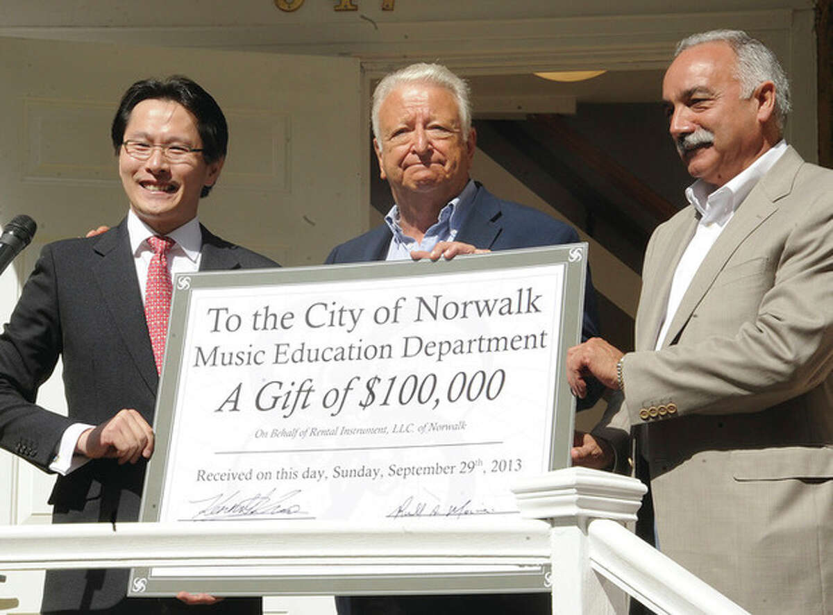 Kenneth Kuo, President/ CEO of Rental instrument, LLC with a check for 100,000 dollars Sunday for Norwalk Mayor Riichard Moccia and Norwalk Superintendent Manuel Rivera at the grand opening of the new Rental Instrument location in Norwalk. Hour photo/Matthew Vinci
