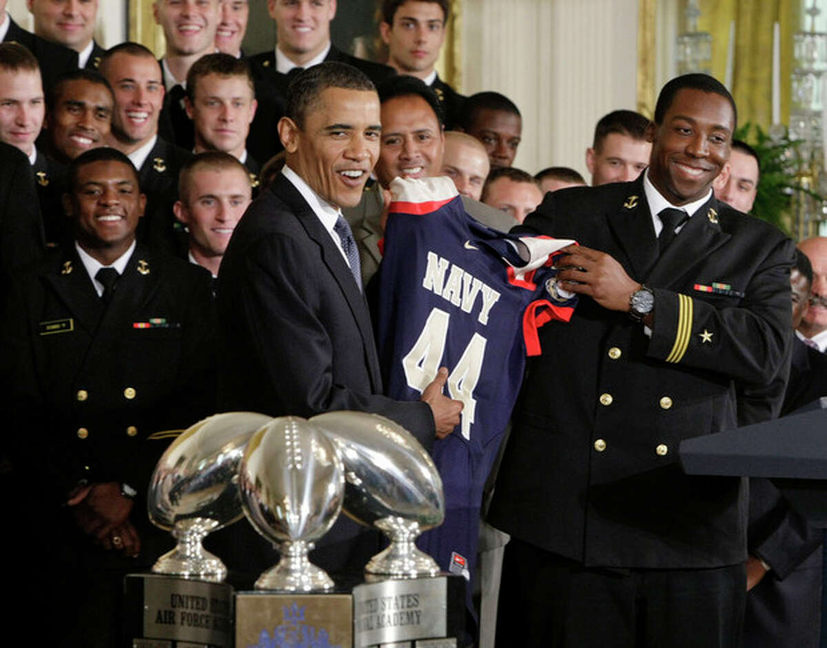 FILE - In this May 3, 2010 file photo, President Barack Obama is presented a Naval Academy football jersey with number 44 by Osei Asante, a senior from Houston, as the Naval Academy's 2009 football team was honored with the Commander In Chief Trophy for victories over rival military academies, in the East Room of the White House in Washington. The Defense Department said Tuesday, Oct. 1, 2013, it has temporarily suspended all sports competitions at the service academies as a result of the partial government shutdown. The decision jeopardizes this weekend's football games _ Air Force at Navy and Army at Boston College. (AP Photo/J. Scott Applewhite, File)