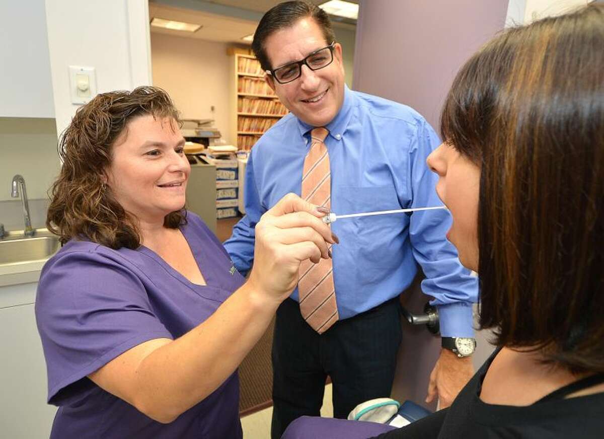 Dr. Joel Evans watches at The Center for Womens Health as Dawn Bria, a medical assistant, swabs the cheek of a client for the BREVAGen predictive risk test, which is used to help indicate how likely a woman is to develop breast cancer over the next five years and throughout her lifetime.