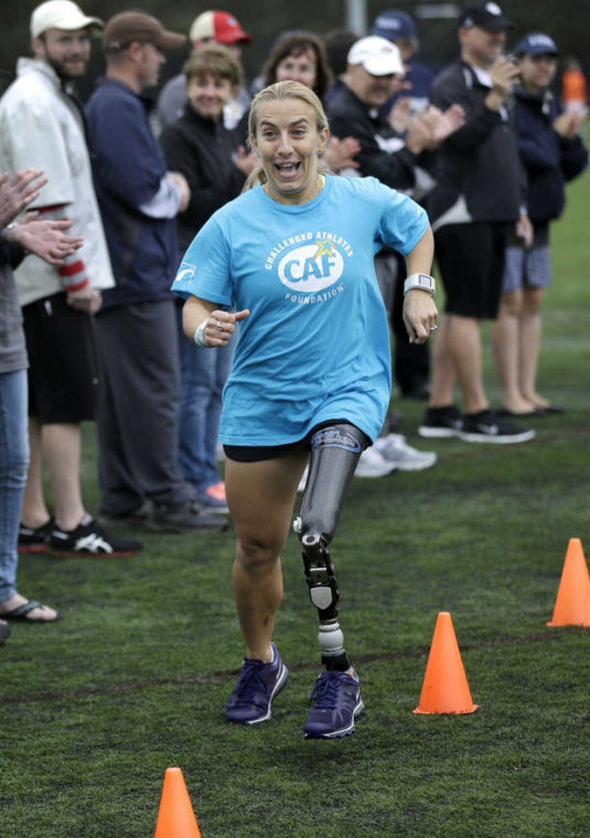 Triathlete Sarah Reinertsen, of San Juan Capistrano, Calif., smiles as she completes an obstacle course during a running clinic for challenged athletes Sunday, Oct. 6, 2013, in Cambridge, Mass. The clinic was run by the Challenged Athletes Foundation, which provides equipment and training for amputees to participate in sports. (AP Photo/Steven Senne)