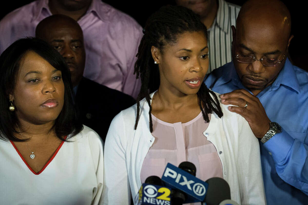 CORRECTS AMY CAREY TO AMY CAREY-JONES - Amy Carey-Jones, center, sister of Miriam Carey, speaks to the media outside the home of her sister Valarie, left, in the Bedford-Stuyvesant neighborhood of Brooklyn, Friday, Oct. 4, 2013, in New York. Law-enforcement authorities have identified Miriam Carey, 34, as the woman who, with a 1-year-old child in her car, led Secret Service and police on a harrowing chase in Washington from the White House past the Capitol Thursday, attempting to penetrate the security barriers at both national landmarks before she was shot to death, police said. The child survived. (AP Photo/John Minchillo)