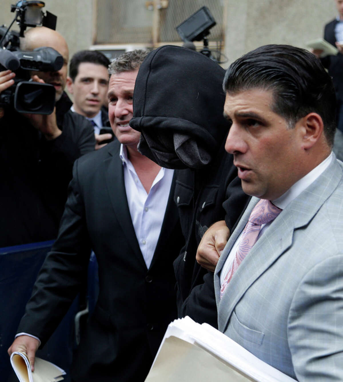 Wojciech Braszczok, center, with face covered, leaves the courthouse in New York, Wednesday, Oct. 9, 2013. Braszczok, an undercover police detective, was charged with gang assault in a motorcycle rally that descended into violence in New York. (AP Photo/Seth Wenig)