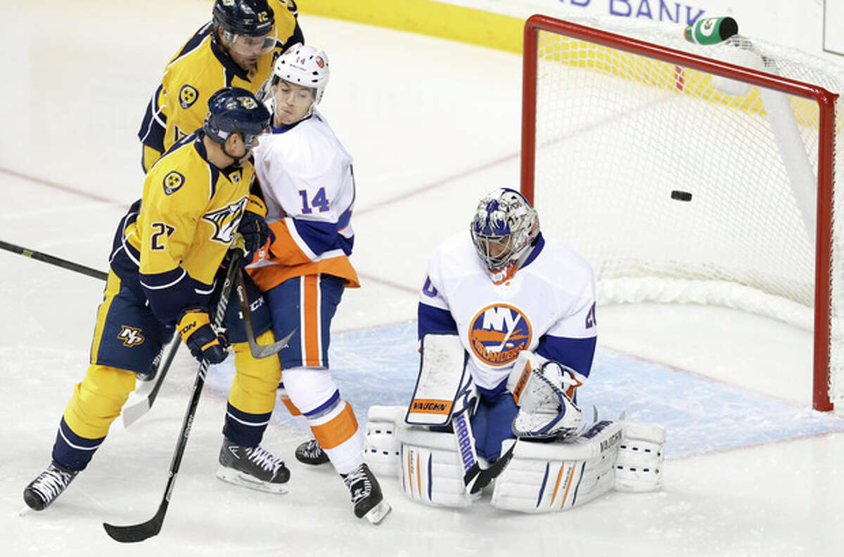 New York Islanders goalie Evgeni Nabokov, right, of Kazakhstan, blocks a shot as Thomas Hickey (14) and Nashville Predators forward Patric Hornqvist (27), of Sweden, battle in front of the net in the first period of an NHL hockey game on Saturday, Oct. 12, 2013, in Nashville, Tenn. (AP Photo/Mark Humphrey)