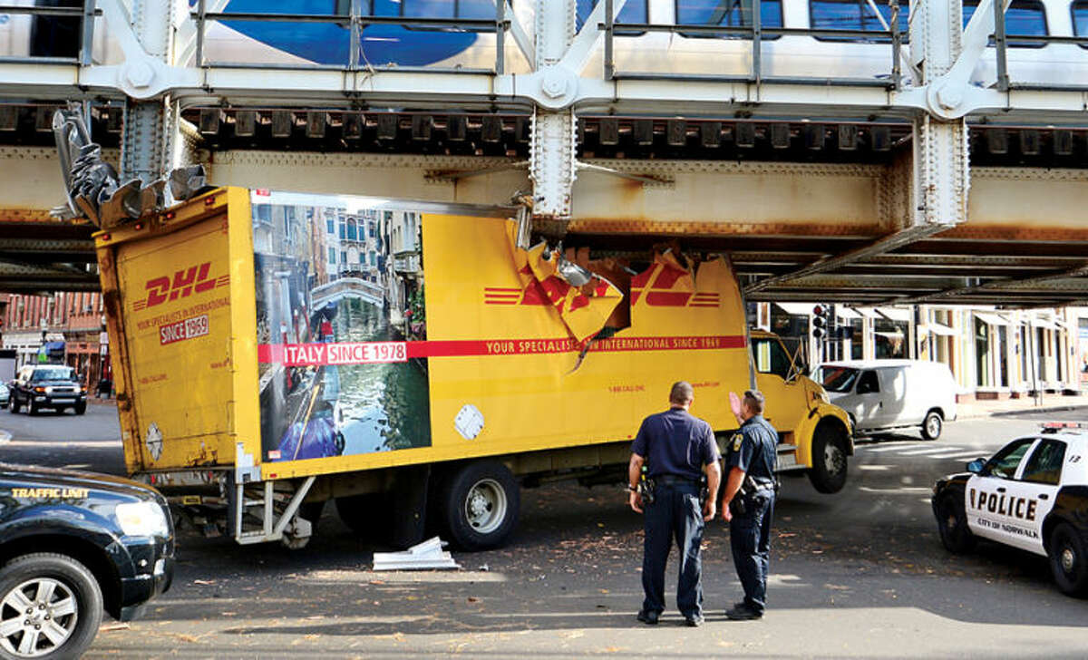 Hour photo / Erik Trautmann Police respond to Washington St and South Main St wherer a DHL delivery truck crashed under the Metro North train tressel.
