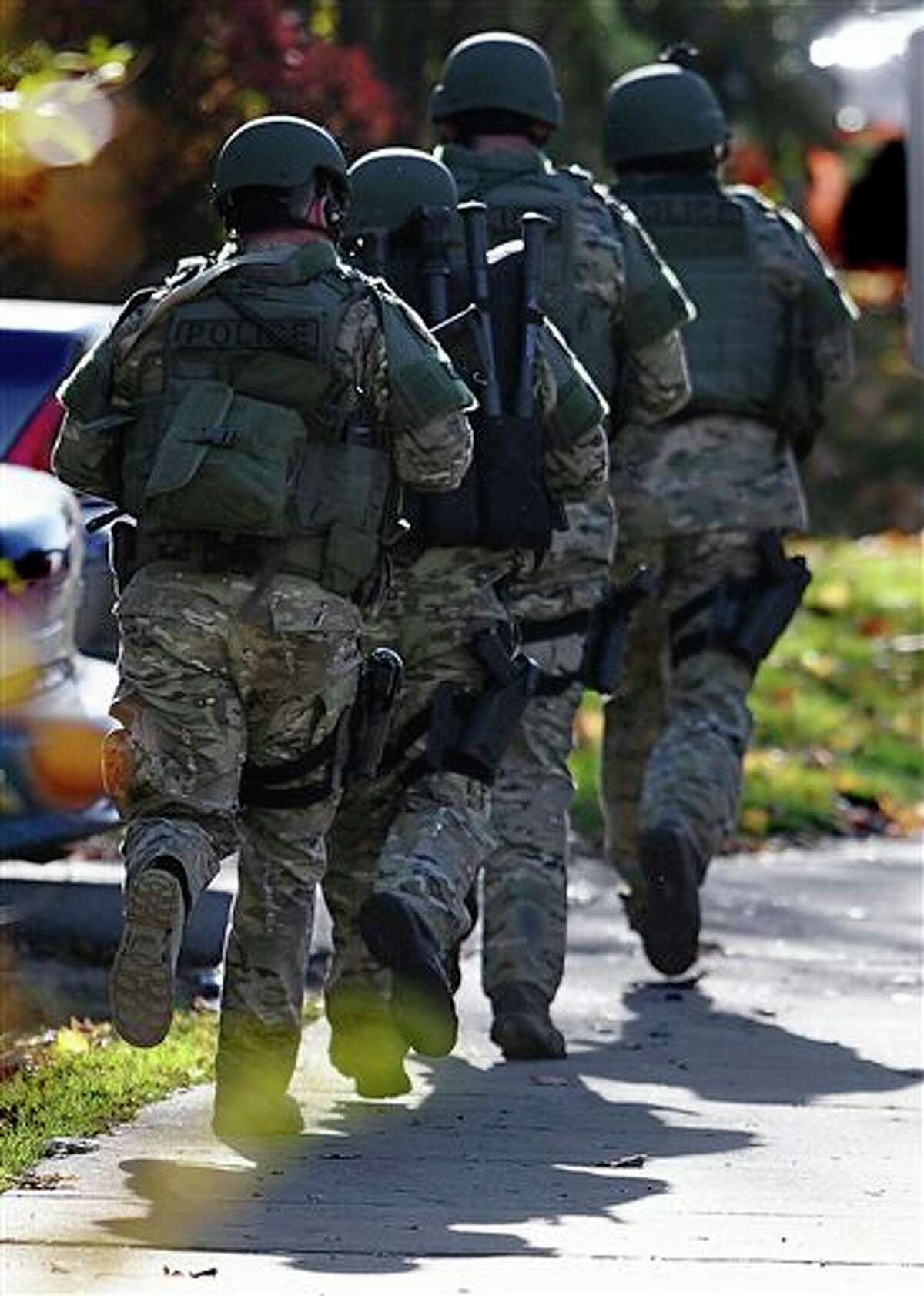 SWAT move in a line on the campus of Central Connecticut State University, Monday, Nov. 4, 2013, in New Britain, Conn. An armed man was spotted on the campus of Central Connecticut State University, prompting a schoolwide lockdown and warnings for students to stay away from windows as police SWAT teams swarmed the area. University spokesman Mark McLaughlin said, "Somebody was seen either with a gun or was thought to have a gun." 