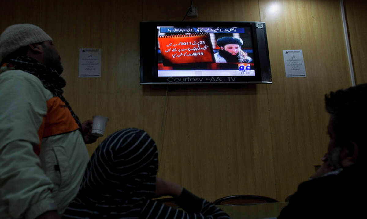 People watch a news report on TV about newly selected leader of Pakistani Taliban leader Mullah Fazlullah at a coffee shop in Islamabad, Pakistan, Thursday, Nov. 7, 2013. The ruthless commander behind the attack on teenage activist Malala Yousafzai as well as a series of bombings and beheadings was chosen Thursday as the leader of the Pakistani Taliban, nearly a week after a U.S. drone strike killed the previous chief. The Arabic on the TV news report reads, "On April 21, 2011, fourteen troops were killed in an attack on a checkpoint in Dir." (AP Photo/B.K. Bangash)