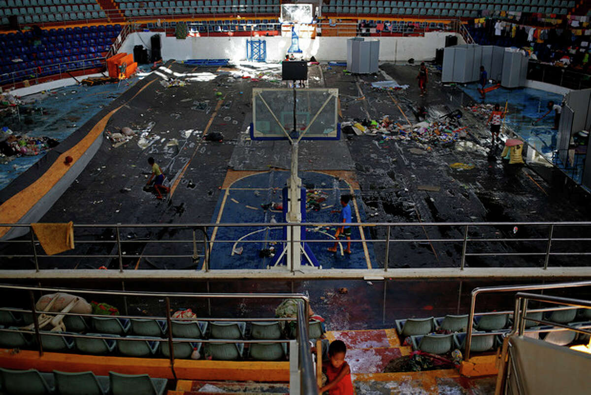 A typhoon survivor sits inside the Tacloban City Convention Center known as the Astrodome Thursday, Nov. 14, 2013, where hundreds of displaced typhoon survivors have set up makeshift living quarters throughout the complex's once bustling shops and popular basketball court. For the thousands of people jamming the Tacloban City Astrodome, the great halls with a solid roof was a heaven-sent refuge when Typhoon Haiyan rammed eastern Philippines on Friday. Evacuated from their homes along the coast in time, they had a place to hide from the furious winds and gigantic water surge. But along with shelter, their constant companion now is misery and hunger. (AP Photo/Vincent Yu)