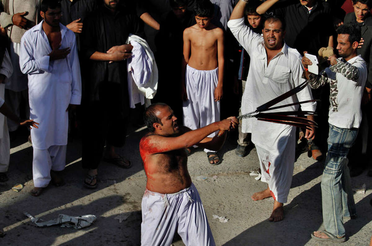A Pakistani Shiite Muslim flagellates himself with knives attached to a chain during an Ashoura procession in Rawalpindi, Pakistan, Friday, Nov. 15, 2013. Ashoura commemorates the martyrdom of Imam Hussein, the grandson of Prophet Muhammad at the Battle of Karbala, Iraq, in the year 680 A.D. (AP Photo/Anjum Naveed)
