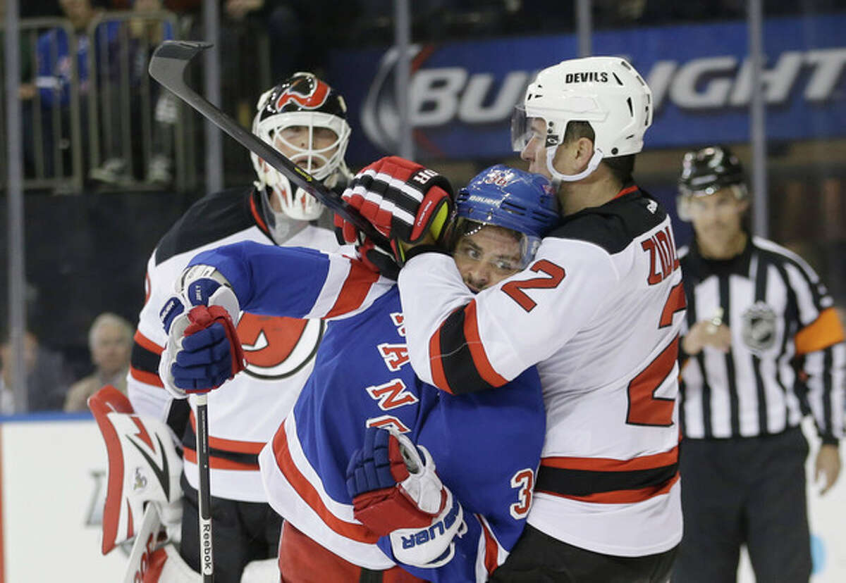 New Jersey Devils' Marek Zidlicky (2) grabs New York Rangers' Mats Zuccarello (36) as Devils goalie Martin Brodeur watches during the second period of an NHL hockey game Tuesday, Nov. 12, 2013, in New York. (AP Photo/Frank Franklin II)