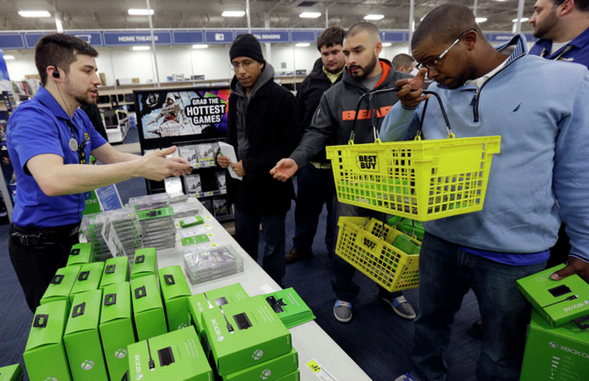 Nikolai Vacca, left, explains newest XBox One accessories to customers at a Best Buy store on Friday, Nov. 22, 2013., in Evanston, Ill. The Xbox One, which includes an updated Kinect motion sensor, cost $500. Microsoft is billing it as an all-in-one entertainment system rather than just a gaming console. (AP Photo/Nam Y. Huh)