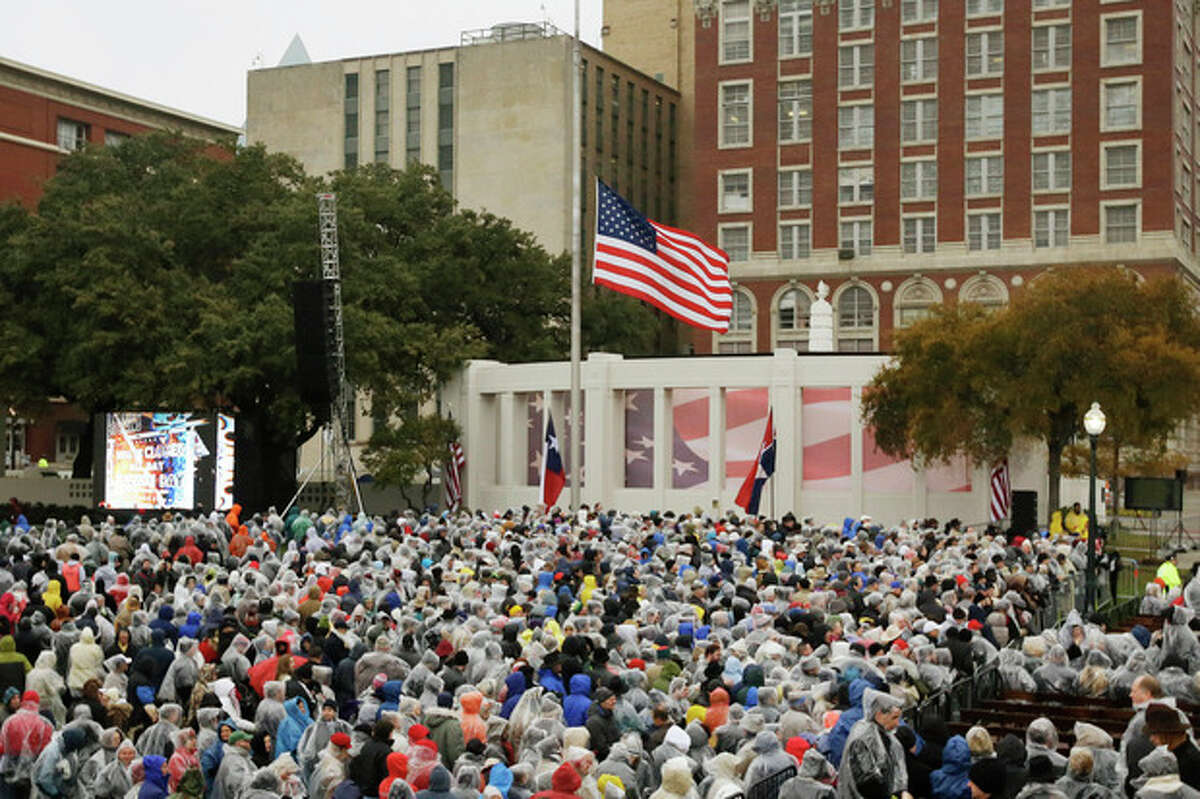 People gather before a ceremony to mark the 50th anniversary of the assassination of John F. Kennedy, Friday, Nov. 22, 2013, at Dealey Plaza in Dallas. President Kennedy's motorcade was passing through Dealey Plaza when shots rang out on Nov. 22, 1963.(AP Photo/Tony Gutierrez)