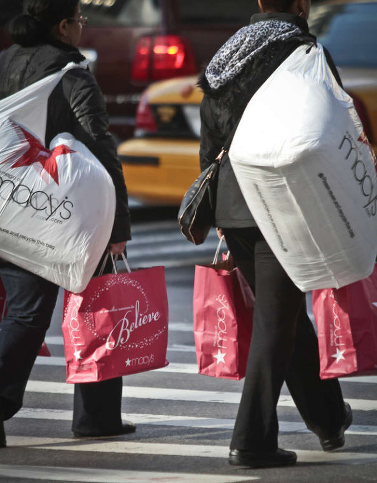 Shoppers carry Macy's bags while crossing an intersection outside Macy's on Saturday, Nov. 23, 2013, in New York. (AP Photo/Bebeto Matthews)