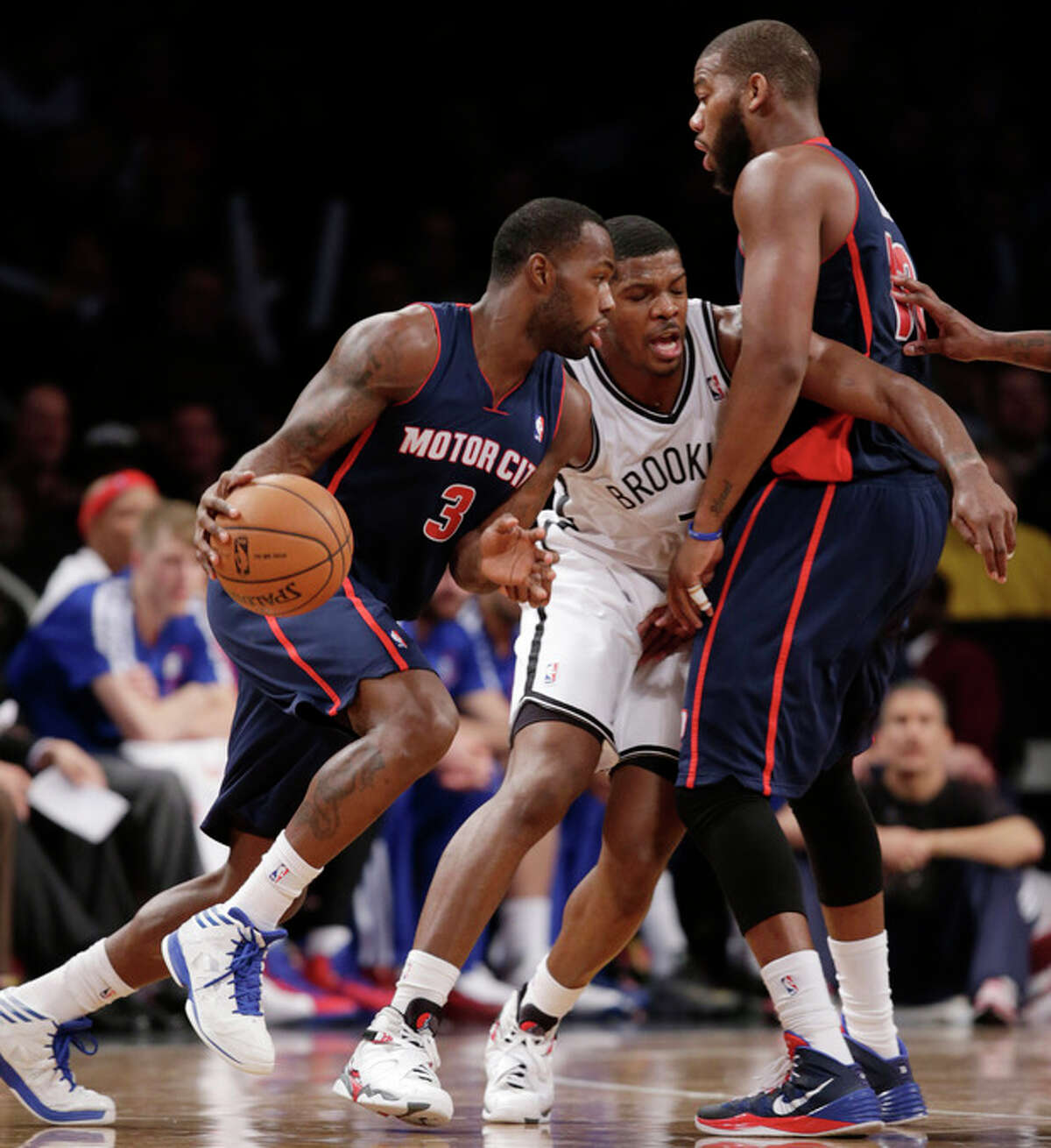 Brooklyn Nets guard Joe Johnson (7) defends as Detroit Pistons guard Rodney Stuckey (3) drives to the basket with Pistons forward Greg Monroe (10) looking on in the first half of an NBA basketball game, Sunday, Nov. 24, 2013, in New York. (AP Photo/Kathy Willens)