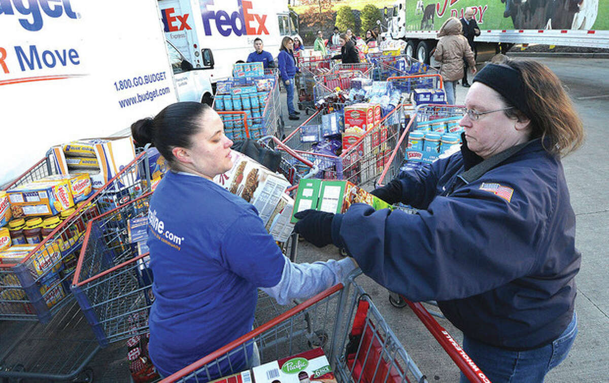 Hour Photo/Alex von Kleydorff . Priceline.com employees Stacey Kurtika and Karen Tappe pass donated groceries from carts to other employees passsing it into trucks at Costco