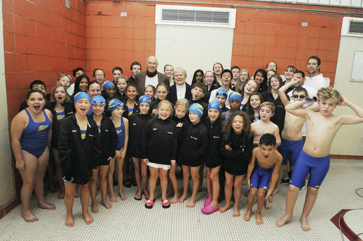Hour photo/Matthew Vinci Terry Philcox, son of legendry swim coach Betty Philcox, and his wife, Carla, pose for a shot with the ZEUS swimmers before Sunday's action at the Betty Philcox Meet at the Norwalk High pool. Nearly 400 young swimmers took part.