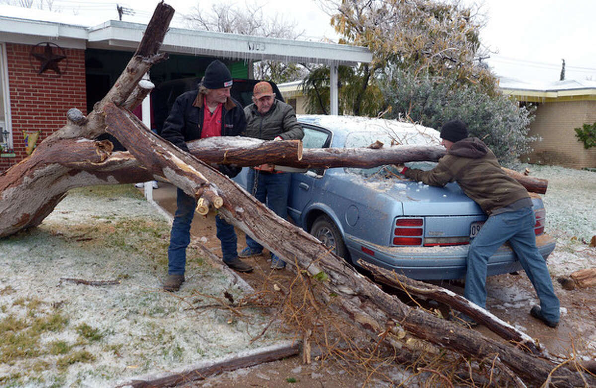 Workers with Duncan Tree Service remove a tree that fell Sunday on Jack Sullivan's Cutlass parked in the driveway of his Odessa, Texas home, on Monday, Nov. 25, 2013. Wintry weather with freezing rain, sleet and snow swept through much of West Texas over the weekend, causing power outages and many tree limbs to break under the weight of the ice. Conditions are forecast to improve during the next couple of days. (AP Photo/Odessa American, Mark Sterkel)
