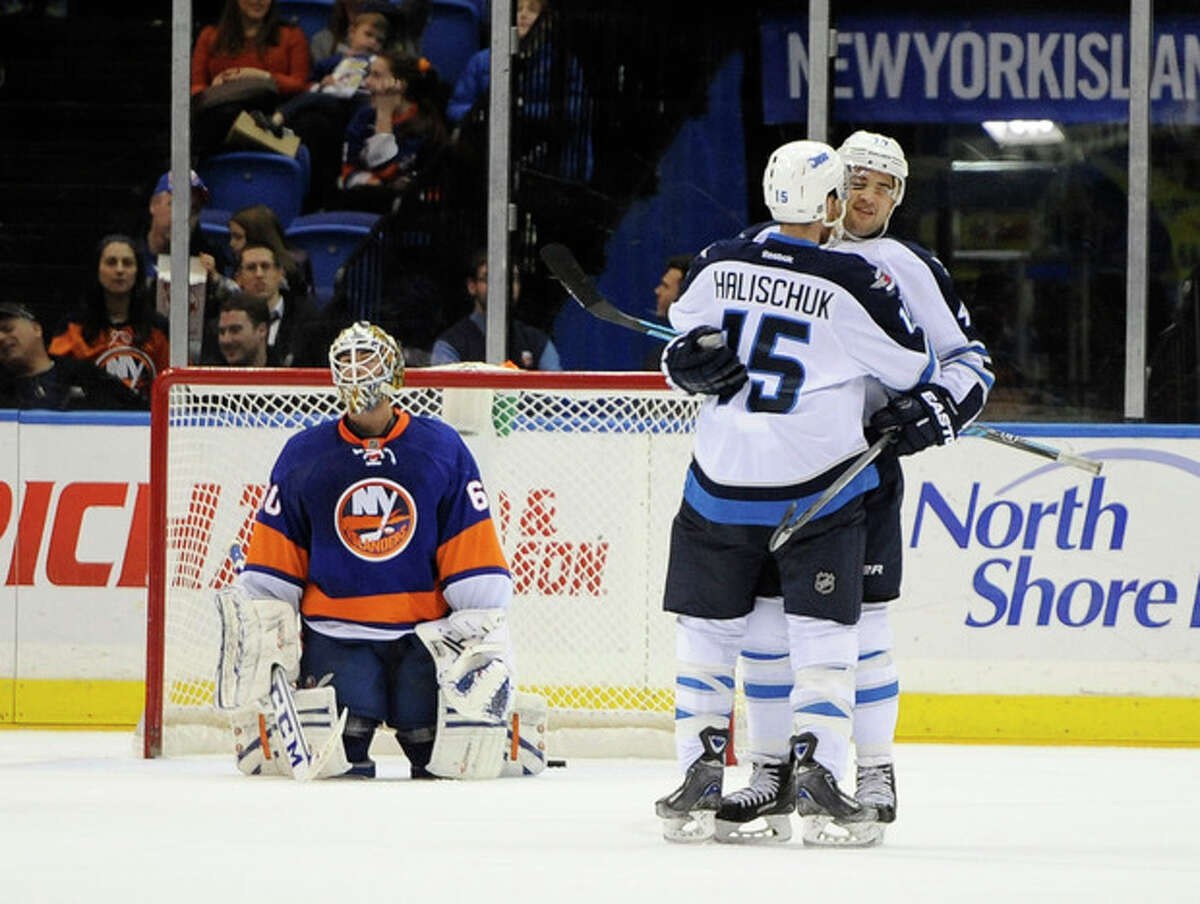 New York Islanders goalie Kevin Poulin (60) reacts as Winnipeg Jets' Devin Setoguchi celebrates his goal with Matt Halischuk (15) in the second period of an NHL hockey game on Wednesday, Nov. 27, 2013, in Uniondale, N.Y. (AP Photo/Kathy Kmonicek)