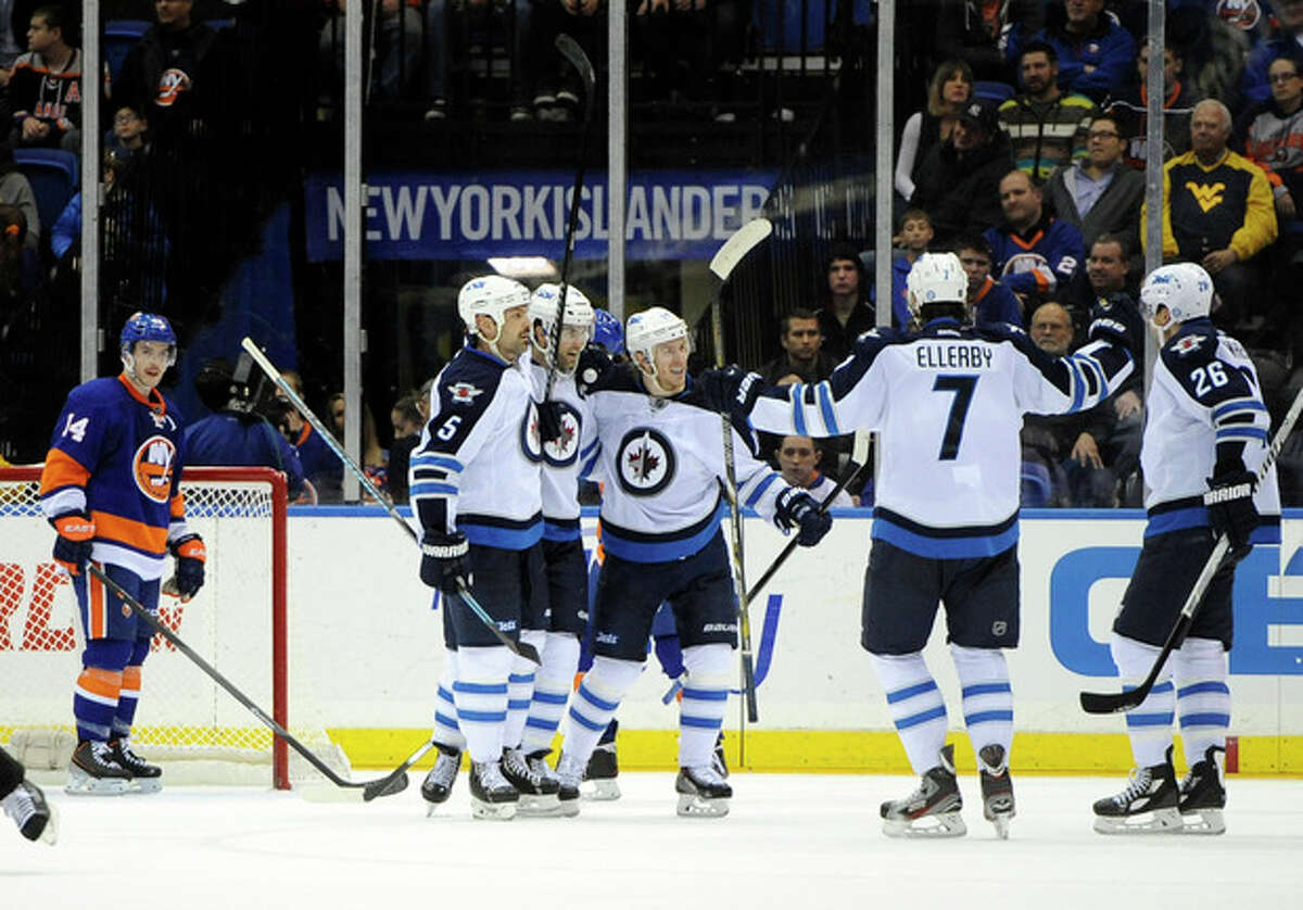 New York Islanders' Thomas Hickey (14) watches Winnipeg Jets' Andrew Ladd (16), second from left, celebrates his goal with teammates in the second period of an NHL hockey game on Wednesday, Nov. 27, 2013, in Uniondale, N.Y. (AP Photo/Kathy Kmonicek)