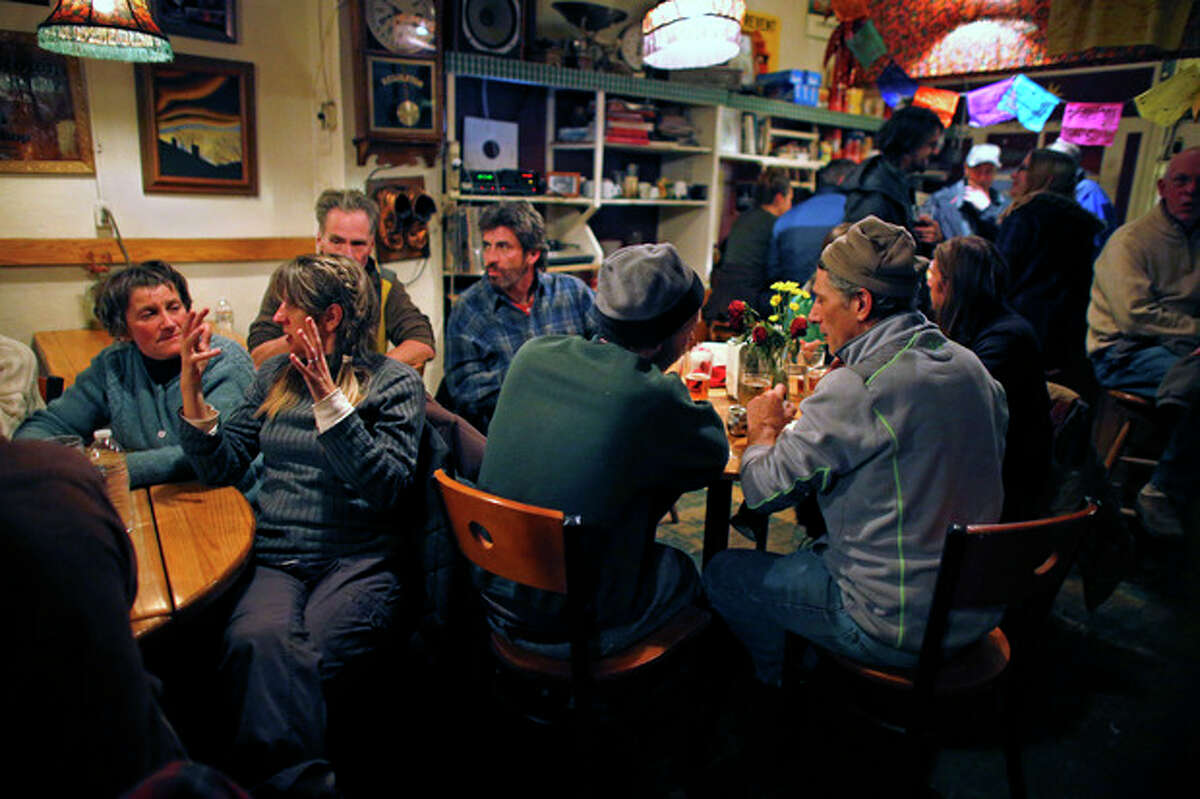 In this Nov. 23, 2013 photo, groups pack around tables talking inside The Merc, a locally-popular bar and restaurant which remains open on Saturday nights despite September's destructive flood, in the Rocky Mountain town of Jamestown, Colo. For a few precious hours every Saturday night, Jamestown looks more like it did before floods and mudslides destroyed a fifth of its homes. Those who stayed and those who fled to rental homes in the nearby Boulder area return to the Jamestown Mercantile, the town?’s meeting place for over 100 years, to share a dinner, then push back the tables and dance to live music. (AP Photo/Brennan Linsley)