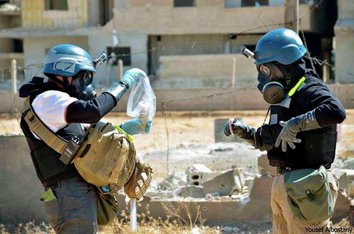 FILE - In this Wednesday, Aug. 28, 2013, file photo, a citizen journalism image provided by the United Media Office of Arbeen which has been authenticated based on its contents and other AP reporting, shows members of the United Nations investigation team take samples from sand near a part of a missile that is likely to be a chemical rocket, according to activists, in the Damascus countryside of Ain Terma, Syria. The Obama administration is offering to destroy some of Syria's deadliest chemical weapons in international waters aboard a nearly 700-foot (213-meter), U.S. government-owned ship, U.S. officials told The Associated Press on Wednesday, Nov. 27, 2013. (AP Photo/Local Committee of Arbeen, File)
