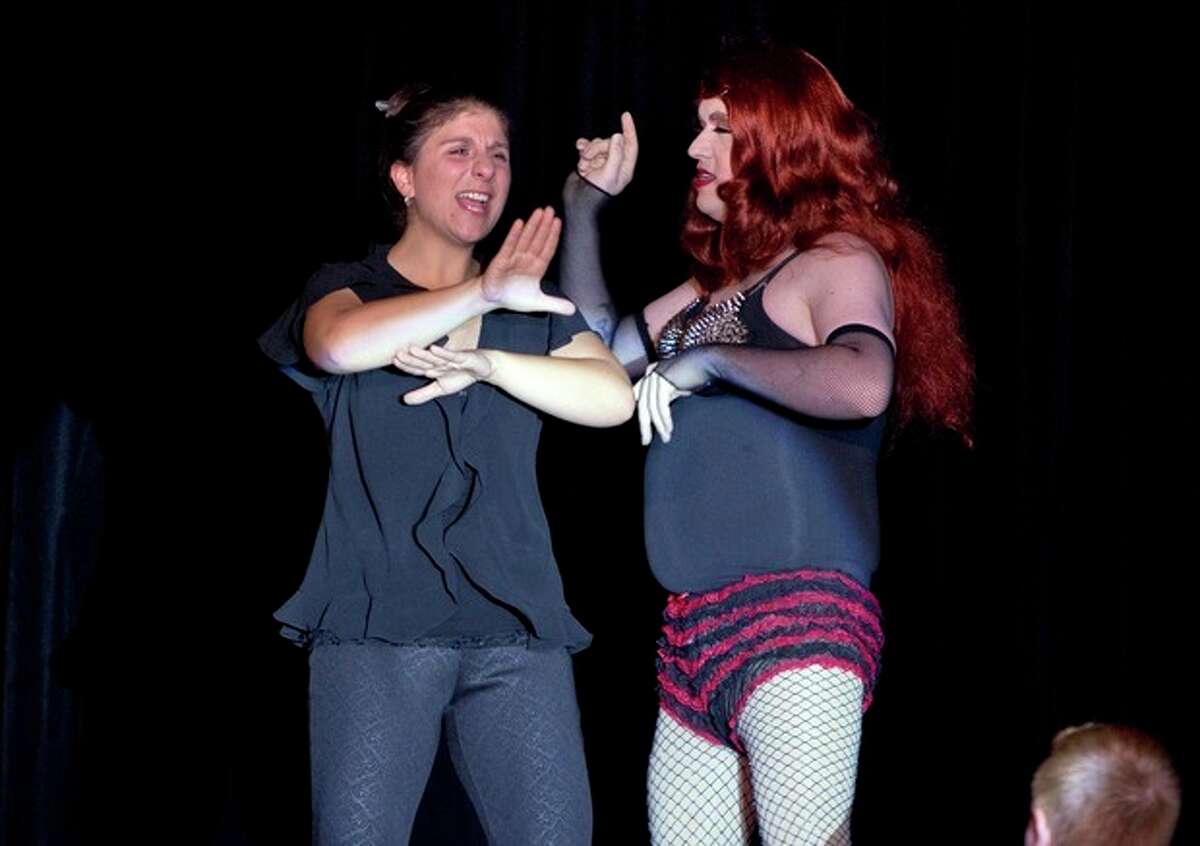 In this Nov. 22, 2013, photo, Holly Maniatty, left, an American Sign Language interpreter, signs during a performance by a contestant in the the Royal Majesty Drag Show and Competition in Portland, Maine. The 33-year-old has become an Internet sensation for the energetic way she uses dance moves, body language and American Sign Language to bring musical performances alive for those who can?’t hear. (AP Photo/Robert F. Bukaty)