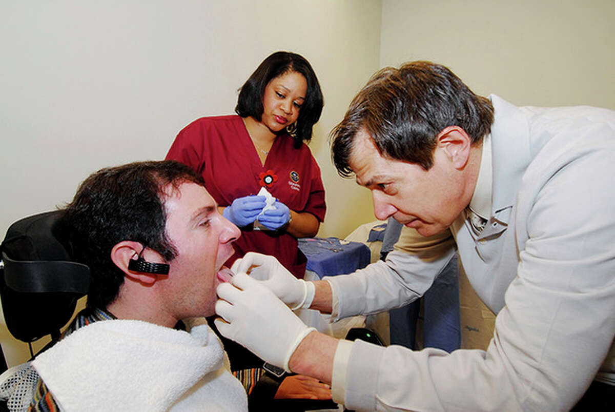 This undated handout photo provided by the Shepherd Center shows Jason DiSanto, left, receiving a tongue piercing at Georgia Tech in Atlanta. An experimental device is letting paralyzed people drive wheelchairs simply by flicking their tongue in the right direction. The Tongue Drive System was developed at Georgia Tech and tested at Shepherd Center in Atlanta. (AP Photo/Georgia Tech, Gary Meek)