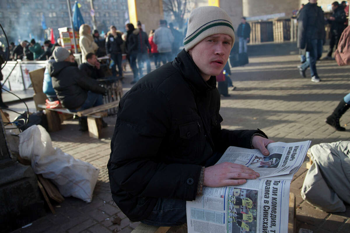 A protester reads a newspaper during a rally in Kiev, Ukraine, on Wednesday, Dec. 4, 2013. A resolution to Ukraine?’s political turmoil remained elusive as thousands of people continued rallying on Kiev?’s Independence Square and besieging key government buildings. (AP Photo/Ivan Sekretarev)