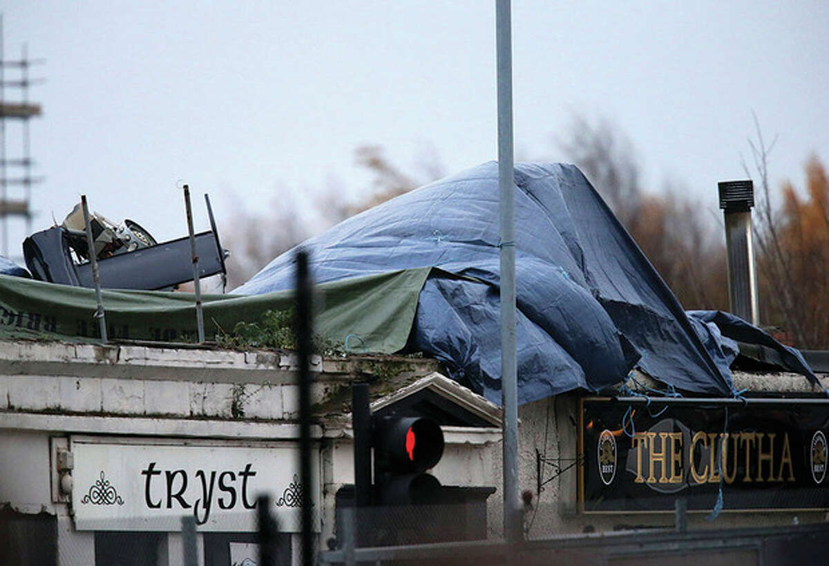 AP Photo / Scott Heppell Part of the helicopter tail fin and rotor is seen after the wind has blown off the sheet covering the scene on Saturday, following the helicopter crash at the Clutha Bar in Glasgow, Scotland. Scottish emergency workers were sifting through wreckage for survivors of a police helicopter crash onto a crowded Glasgow pub that has killed at least one person and injured more than two dozen. The Clutha pub, near the banks of the River Clyde, was packed Friday night and a ska band was in full swing when the chopper slammed through the roof. The number of fatalities is expected to rise, officials said.
