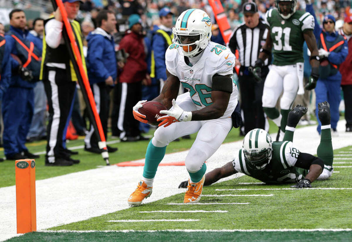 Miami Dolphins running back Lamar Miller (26) steps out of bounds after being hit by New York Jets defensive back Aaron Berry (22) before the goal line during the first half of an NFL football game, Sunday, Dec. 1, 2013, in East Rutherford, N.J. (AP Photo/Seth Wenig)