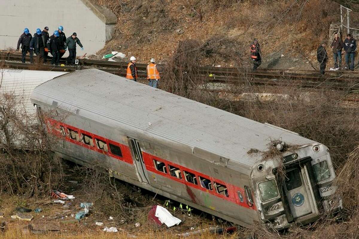 Emergency rescue personnel, top left, remove the body of a victim from the site of a train derailment, Sunday, Dec. 1, 2013 in the Bronx borough of New York. (AP Photo/Mark Lennihan)
