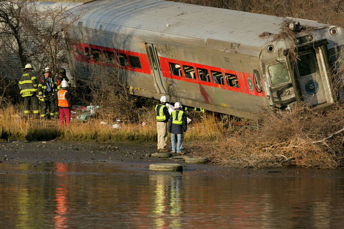 Officials with the National Transportation Safety Board inspect a derailed Metro North commuter train where it almost fell into the Harlem River, Sunday, Dec. 1, 2013 in the Bronx borough of New York. The Metro-North train derailed on a curved section of track early Sunday, coming to rest just inches from the water, killing at least four people and injuring more than 60, authorities said. (AP Photo/Mark Lennihan)