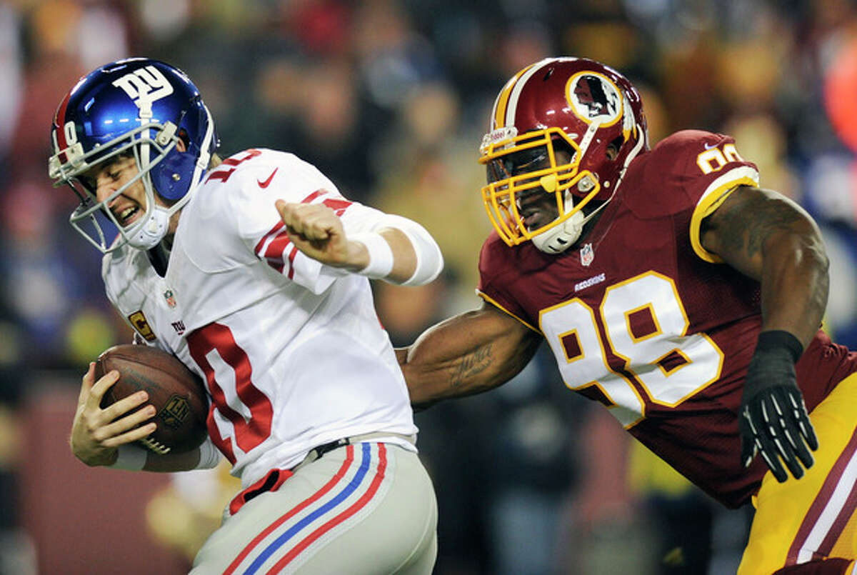 New York Giants quarterback Eli Manning, left, is sacked by Washington Redskins outside linebacker Brian Orakpo (98) during the first half of an NFL football game Sunday, Dec. 1, 2013, in Landover, Md. (AP Photo/Nick Wass)