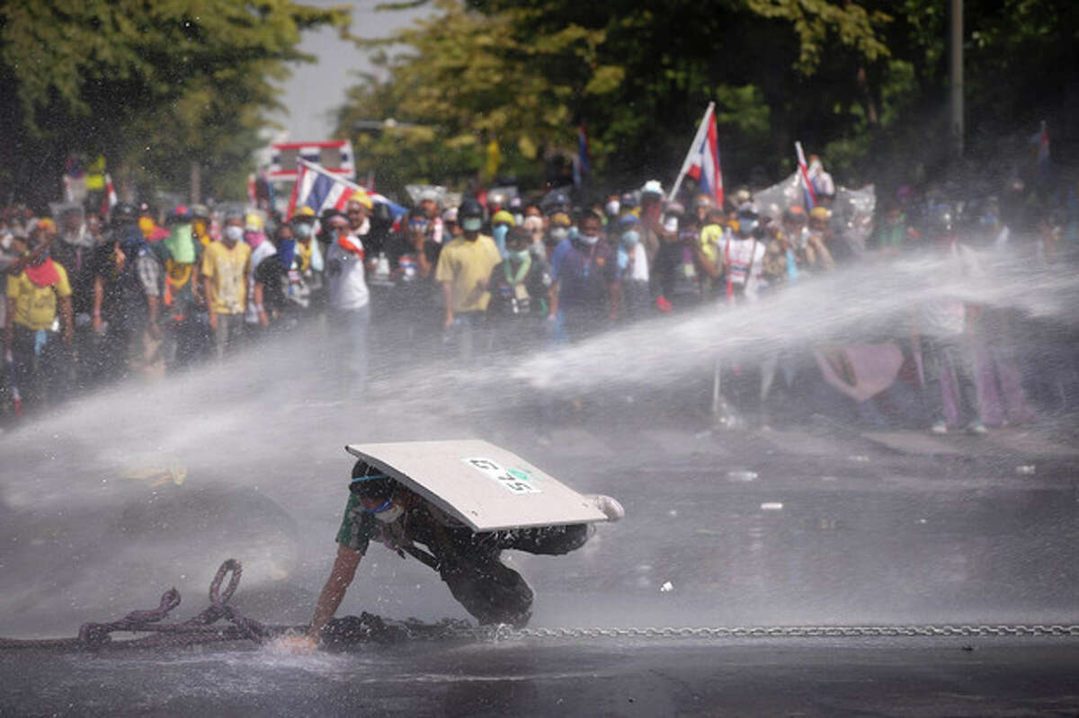 An Anti-government protester falls as he is hit by water cannon by police in Bangkok, Thailand, Monday, Dec 2, 2013. After a weekend of chaos in pockets of Bangkok, protesters vowed to push ahead with plans to topple Prime Minister Yingluck Shinawatra by occupying her office compound along with other key government buildings. Police again used tear gas on thousands of protesters on Monday after repeatedly driving them back with similar attacks throughout Sunday. (AP Photo/Vincent Thian)