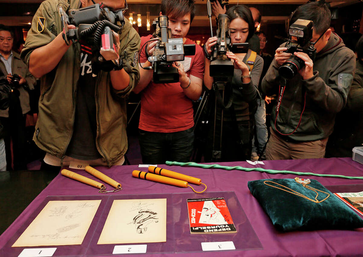 Bruce Lee?’s most iconic martial arts weapons, including a pair of yellow lacquered wooden nunchaku, second from left, are displayed during an auction preview in Hong Kong, Monday, Dec. 2, 2013. It?’s part of a collection of 14 items including clothing and props going on the block on Thursday. Spink auction house estimates props from his movie ?“Game of Death?” to be sold include the nunchaku expected to fetch $26,000-$38,700. (AP Photo/Vincent Yu)