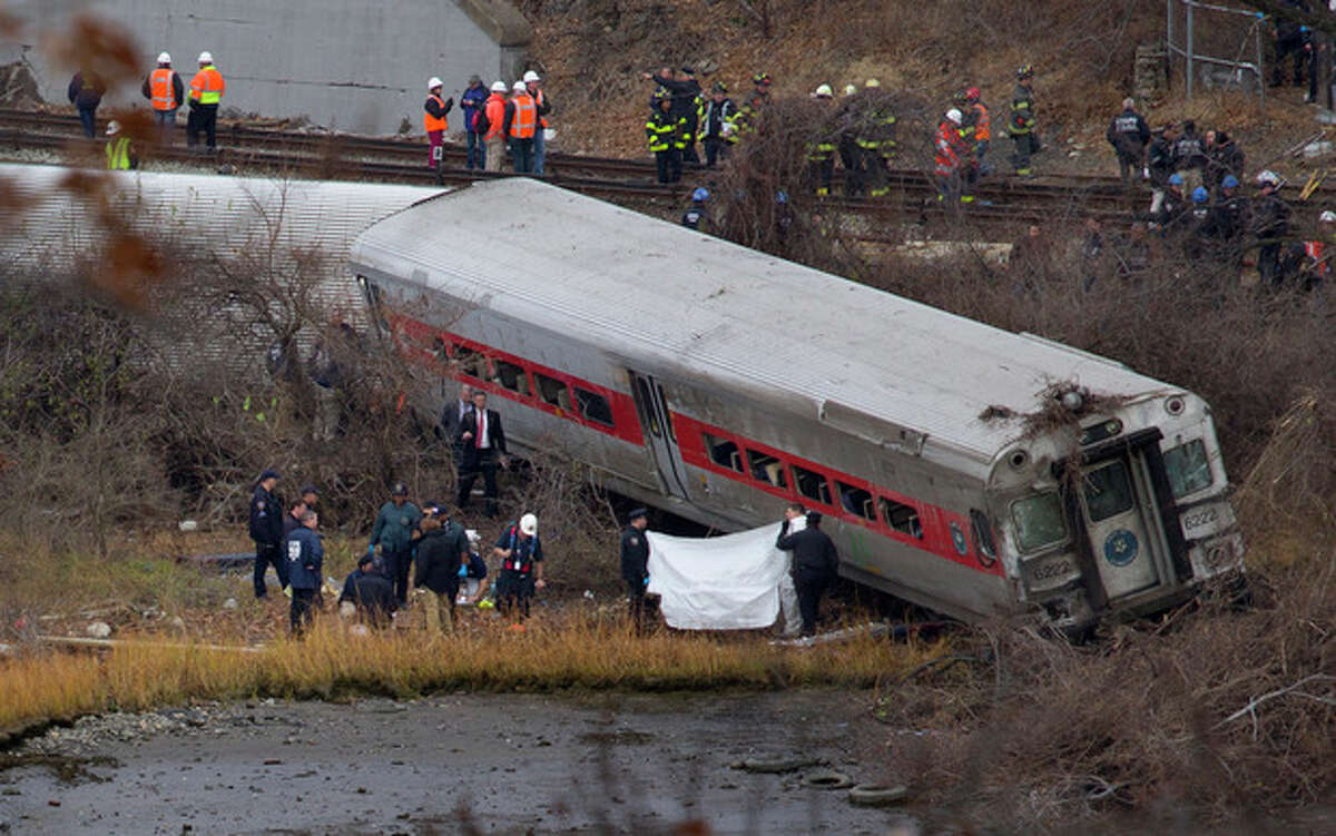 Viewed from Manhattan, first responders and others work at the scene of a derailed Metro North passenger train in the Bronx borough of New York Dec. 1, 2013. The train derailed on a curved section of track in the Bronx early Sunday, coming to rest just inches from the water, killing at least four people and injuring more than 60, authorities said. Police divers searched the waters to make sure no passenger had been thrown in, as other emergency crews scoured the surrounding woods. (AP Photo/Craig Ruttle)