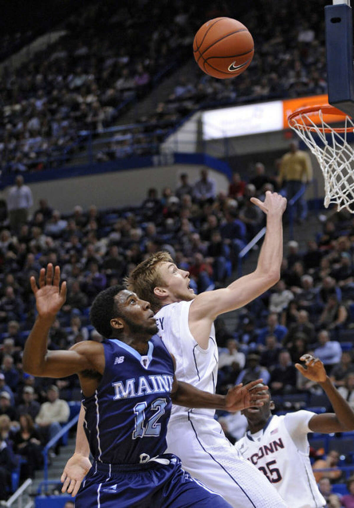 Connecticut's Niels Giffey (5) and Maine's Xavier Pollard (12) fight for a rebound during the first half of an NCAA college basketball game, in Hartford, Conn., on Friday, Dec. 6, 2013. (AP Photo/Fred Beckham)