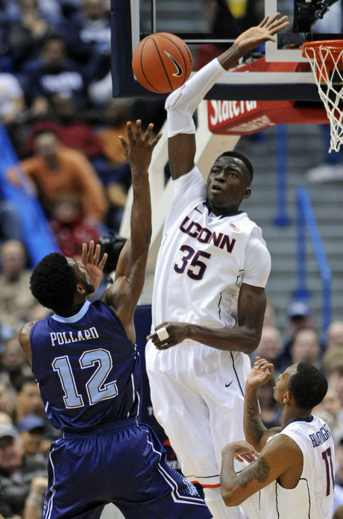 Maine's Xavier Pollard (12) tries to shoot over Connecticut's Amida Brimah (35) during the first half of an NCAA college basketball game, in Hartford, Conn., on Friday, Dec. 6, 2013. (AP Photo/Fred Beckham)